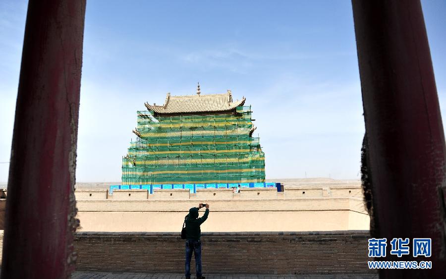 一名游客在正在维修的嘉峪关城楼上拍照