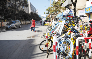 很多共享单车横七竖八地堆放在新闻路人行道上。