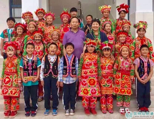 周林夫妇在巍山县凤山春苗小学教学楼前与彝族孩子们合影。