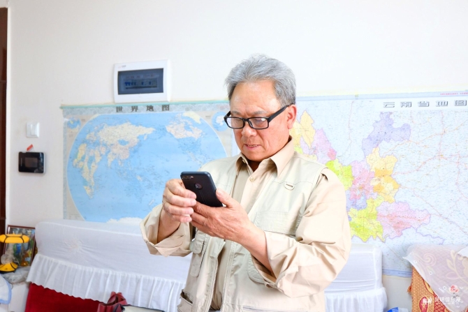 钟远财在手机里查找储存的照片。记者曹月 摄