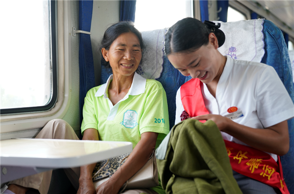 昆明至攀枝花6162次慢火车乘务员帮助乘车大姐缝衣服，两人又说有笑，聊起家常。