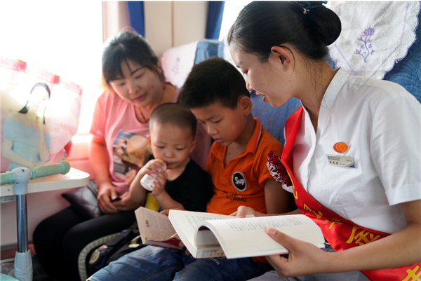 慢火车志愿者在列车“读书角”，与乘车的小学生一起朗读文章，相互交流、探讨文章中的故事情节。