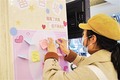 春节期间，一名结束医学观察的武汉滞留旅客在留言墙上写下感谢和祝福的话，传递信心力量。新华社发