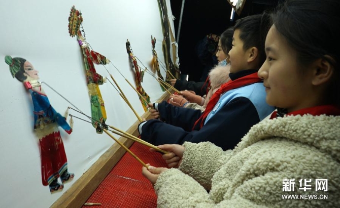 12月15日，在位于河南省许昌市建安区苏桥镇的河南省润知非物质文化遗产研学旅行基地，小学生在体验操作皮影。