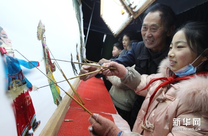 12月15日，在位于河南省许昌市建安区苏桥镇的河南省润知非物质文化遗产研学旅行基地，许昌陈氏皮影第四代传人陈志国（右二）指导学生学习皮影戏。新华社发（牛书培 摄）