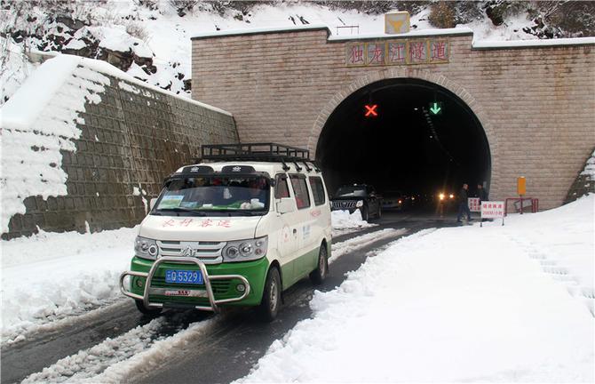 王军的农村客运车辆雪花飘飘中驶出独龙江公路高黎贡山隧道。王靖生摄.jpg