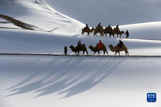 1月14日,游客在甘肃省敦煌市鸣沙山月牙泉景区游览。 近日,受冷空气影响,我国多地迎来降雪天气。 新华社发(张晓亮 摄)