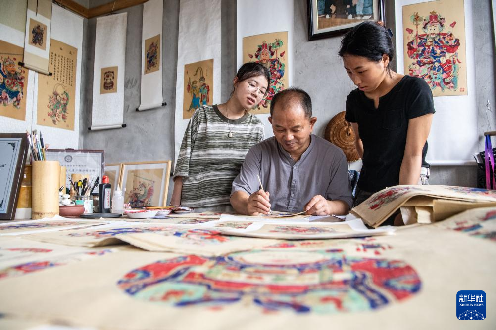8月10日,梁平木版年画代表性传承人徐家辉(中)在演示年画上色。 8月10日,梁平木版年画代表性传承人徐家辉(中)在演示年画上色。